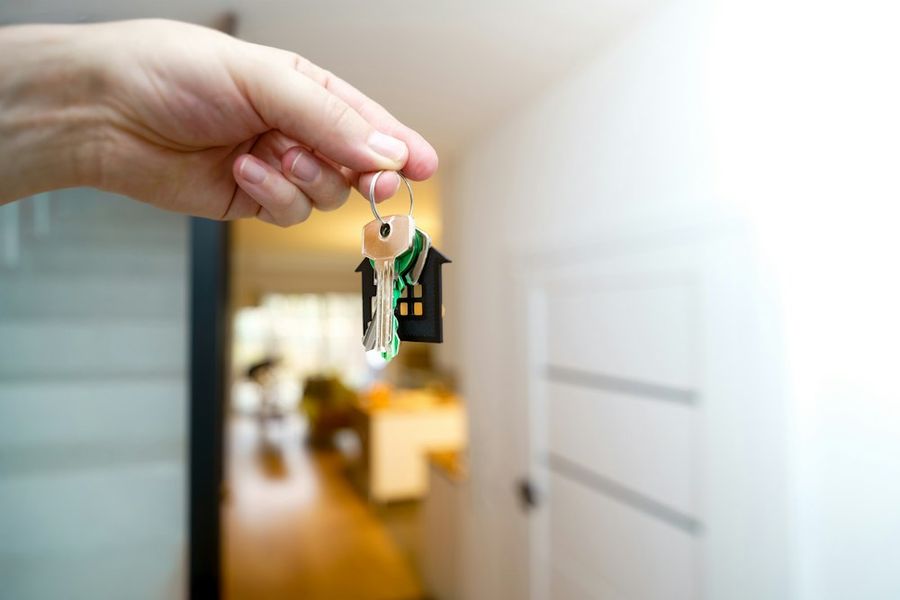 Une main tend les clés d'un logement sur le pas de la porte